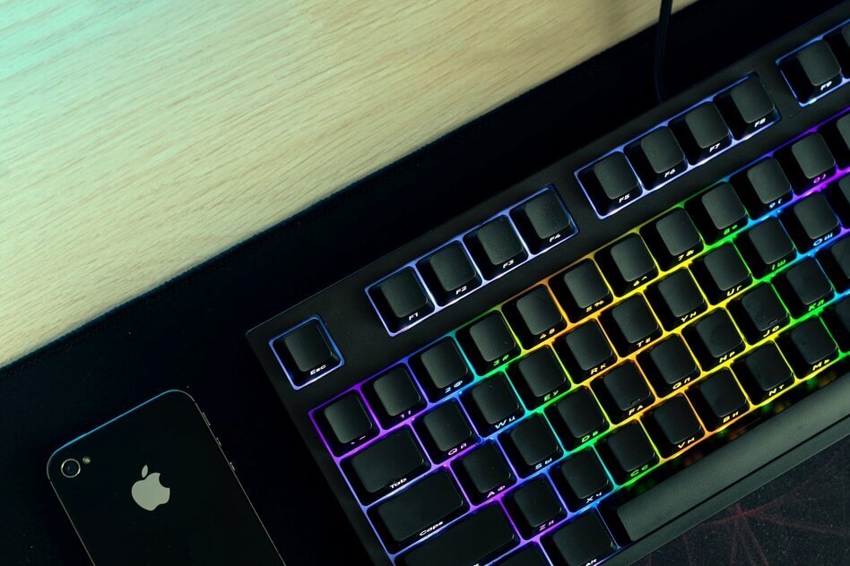 black gaming keyboard with colored backlight near iphone